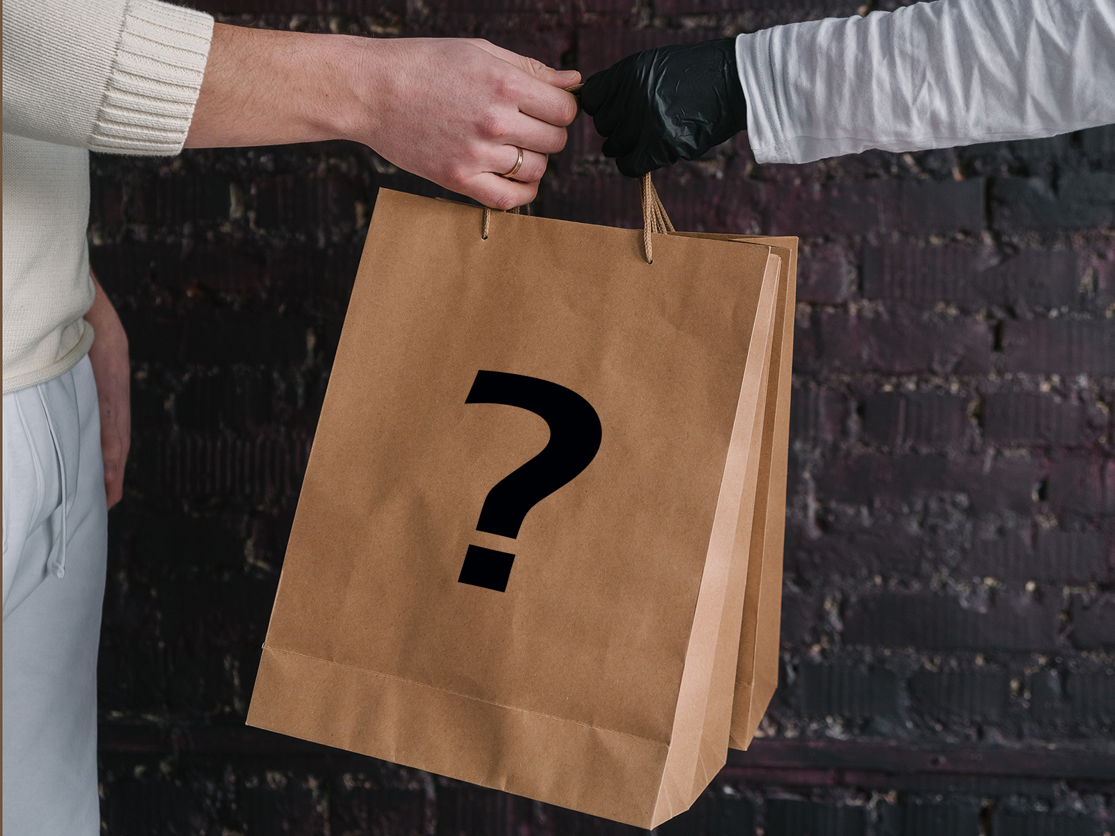 Kinsey Investigations Mystery Shopper Services - Two hands from two different people who are not pictured hold onto the handle of a brown shopping bag that is stamped with a large black question mark.