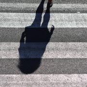 Kinsey Investigations Female Private Investigators - The shadow of someone with long hair is pictured on white and gray striped pavement.