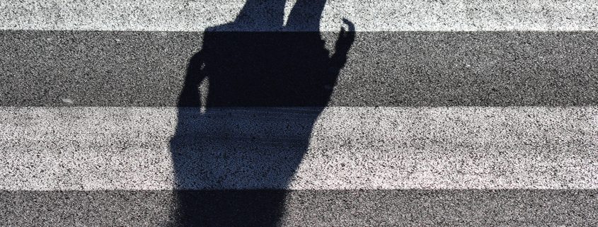 Kinsey Investigations Female Private Investigators - The shadow of someone with long hair is pictured on white and gray striped pavement.