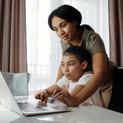 Kinsey Investigations Internet Safety Tips - A mother leans over a school age child as they work together on a laptop computer
