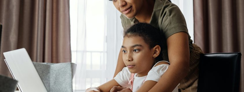 Kinsey Investigations Internet Safety Tips - A mother leans over a school age child as they work together on a laptop computer