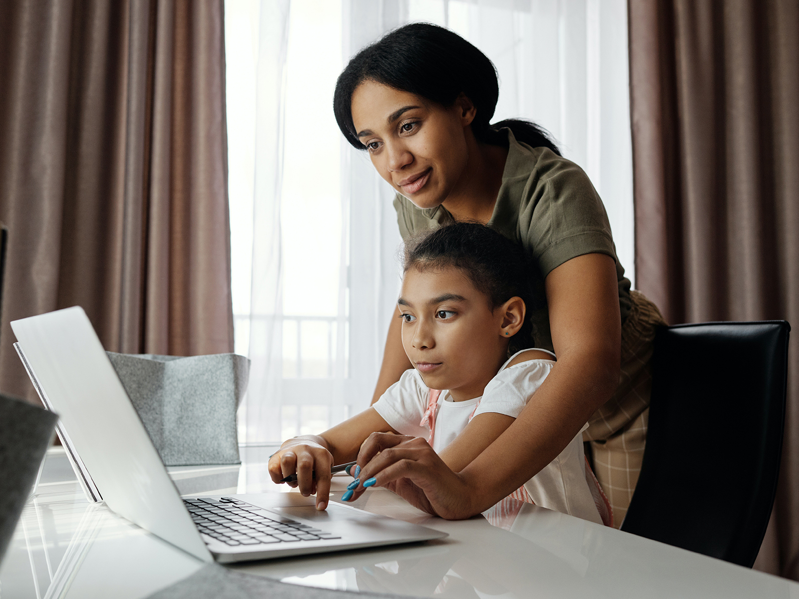 Kinsey Investigations Internet Safety Tips - A mother leans over a school age child as they work together on a laptop computer
