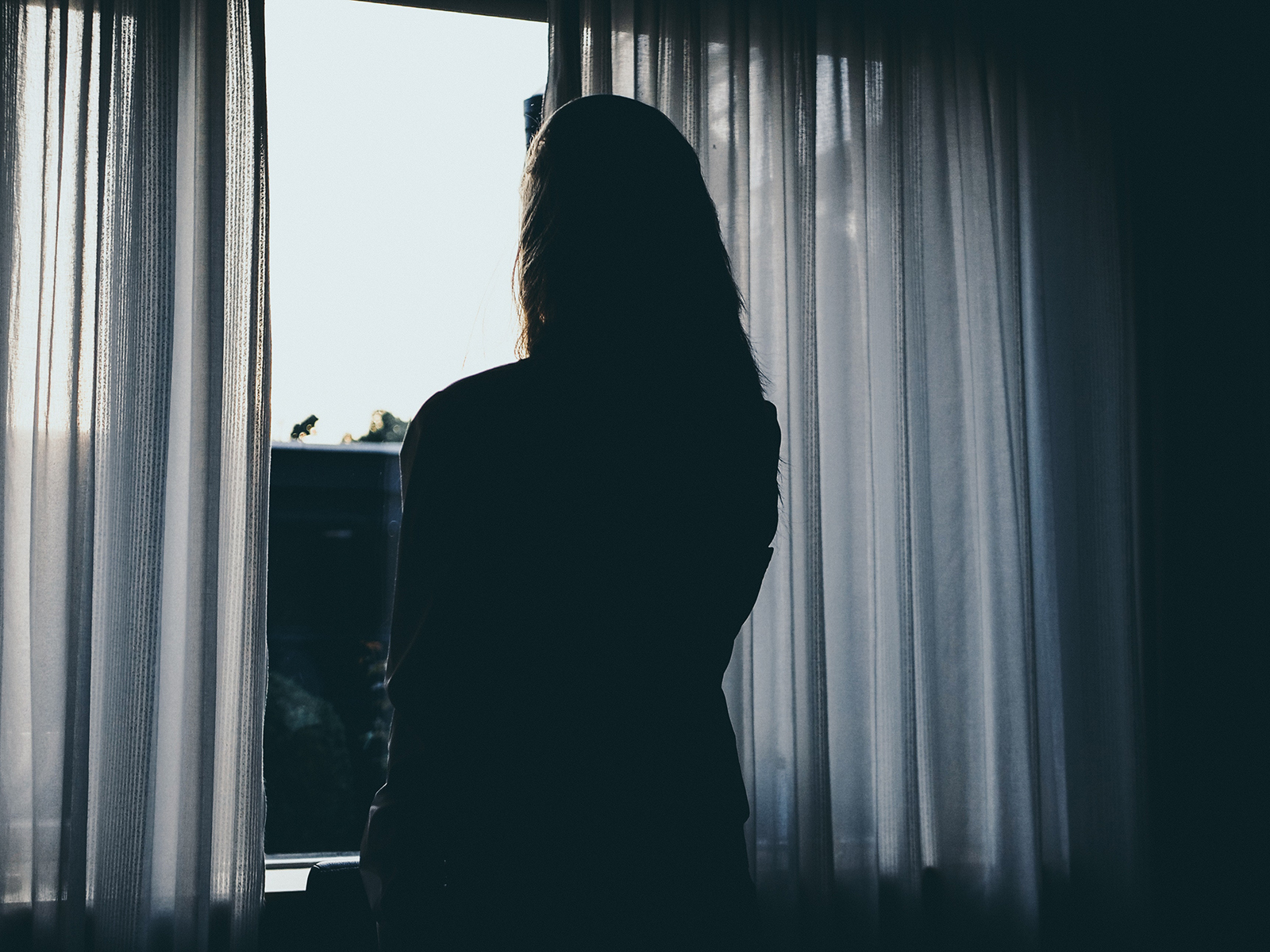 Kinsey Investigations Alimony Cohabitation Private Investigations - A woman is silhouetted against a window as she looks out of it.