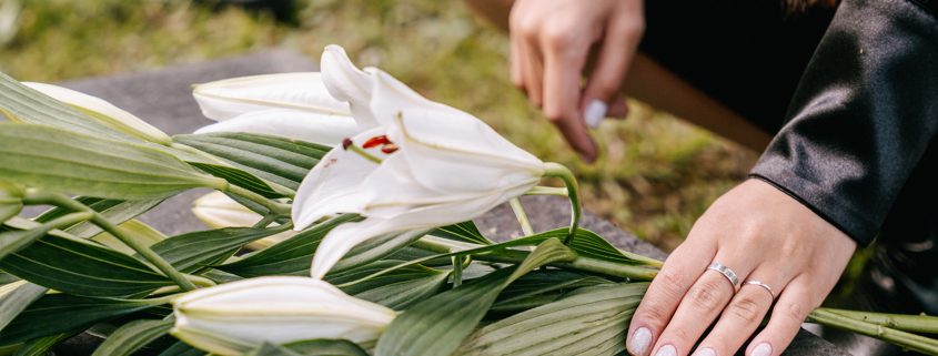 Kinsey Investigations Wrongful Death Cases - The hands of an unseen person place flours on a grave marker.