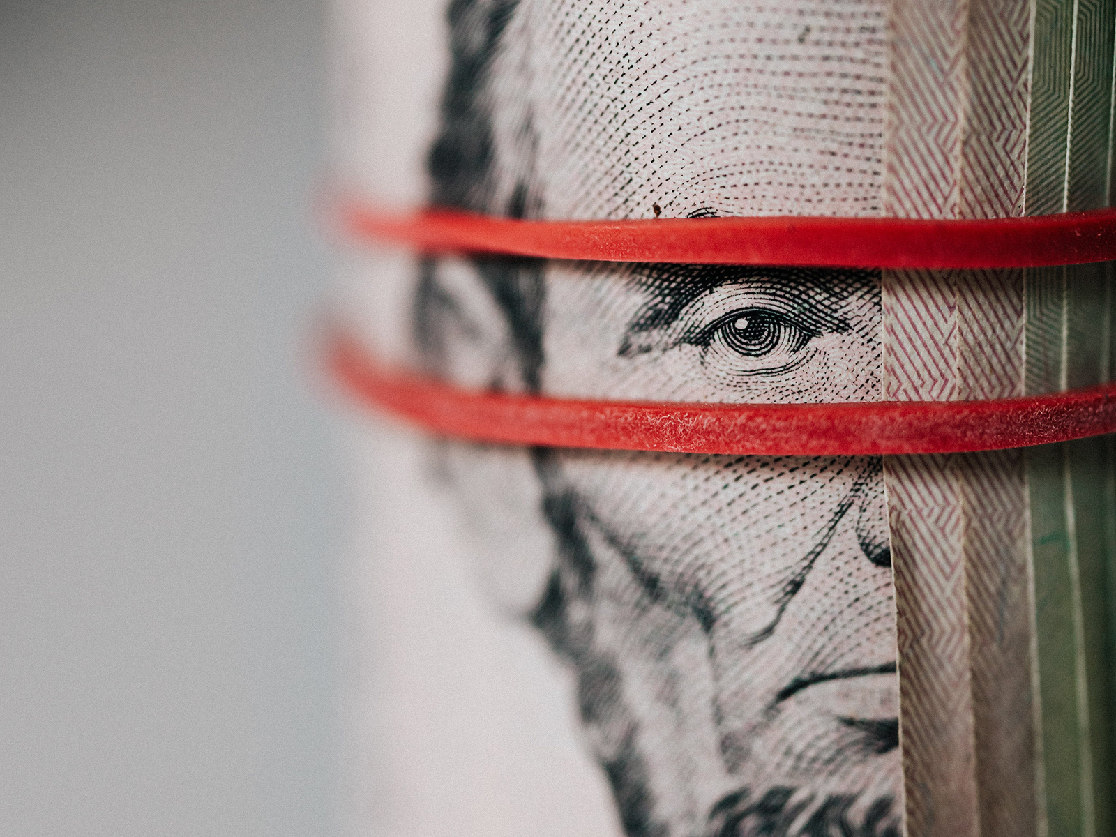 Kinsey Investigations Workers Comp Fraud - A roll of US dollars is held with red rubber bands