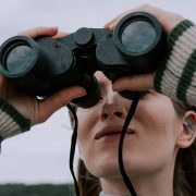 KinseyInvestigations.com Surveillance Investigations - A woman looks through a pair of binoculars