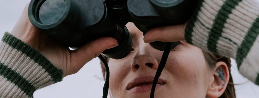 KinseyInvestigations.com Surveillance Investigations - A woman looks through a pair of binoculars