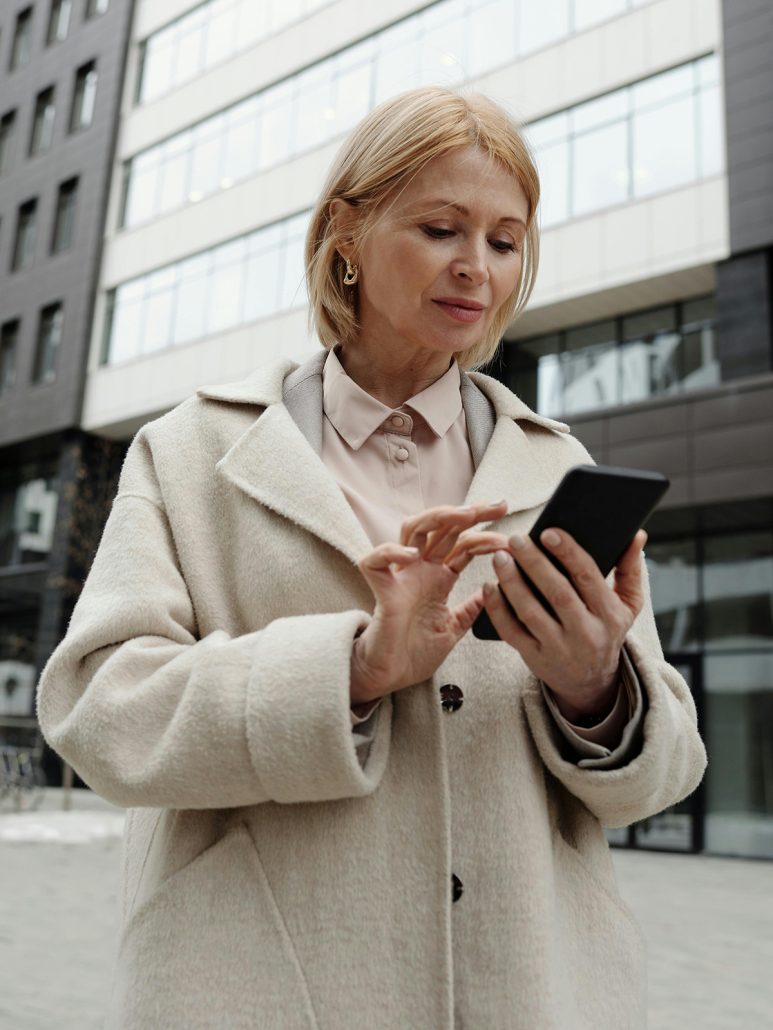 KinseyInvestigations.com What Do Private Detectives do - A woman in front of an office building checks her cellphone.