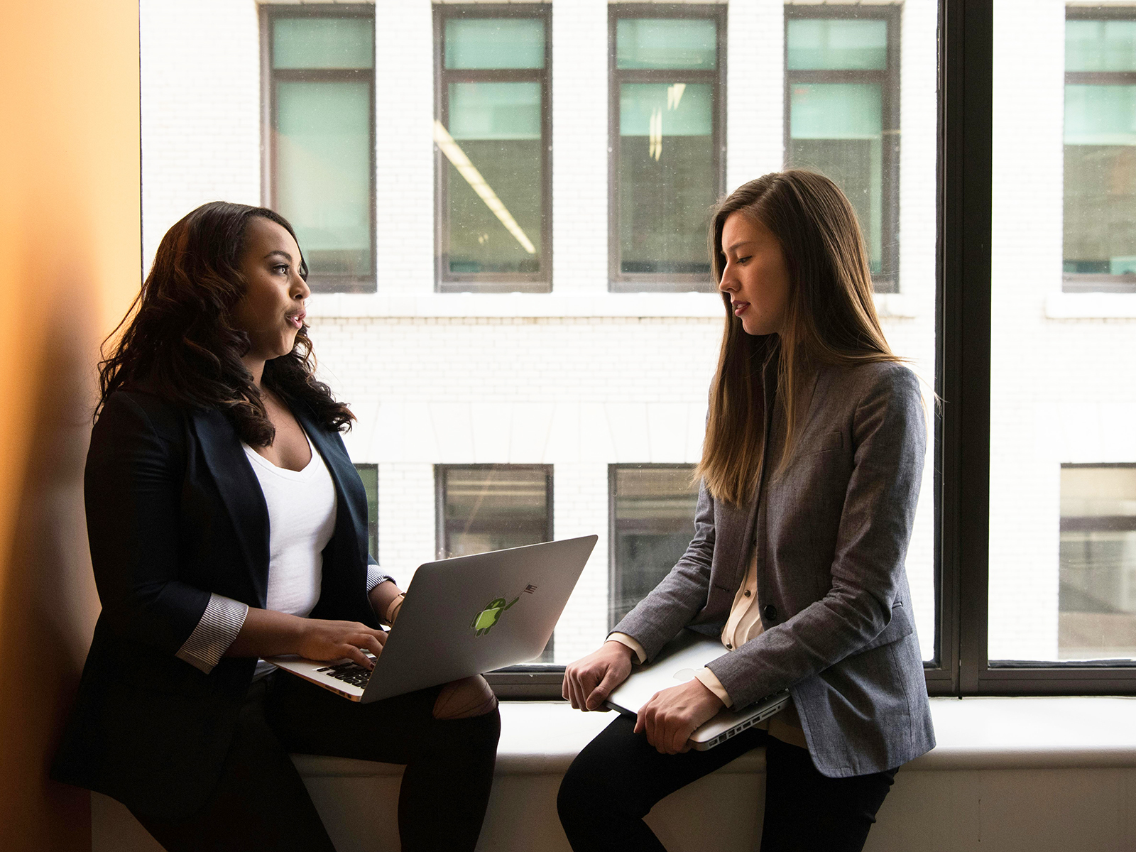KinseyInvestigations.com Activity Check Investigations - Two business women sit together with a laptop computer.