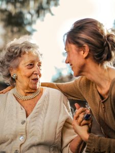 KinseyInvestigations.com Activity Checks - An older woman smiles at a younger woman as they sit together.