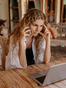 KinseyInvestigations.com Private Investigator Costs - A woman in front of a laptop computer makes a phone call.