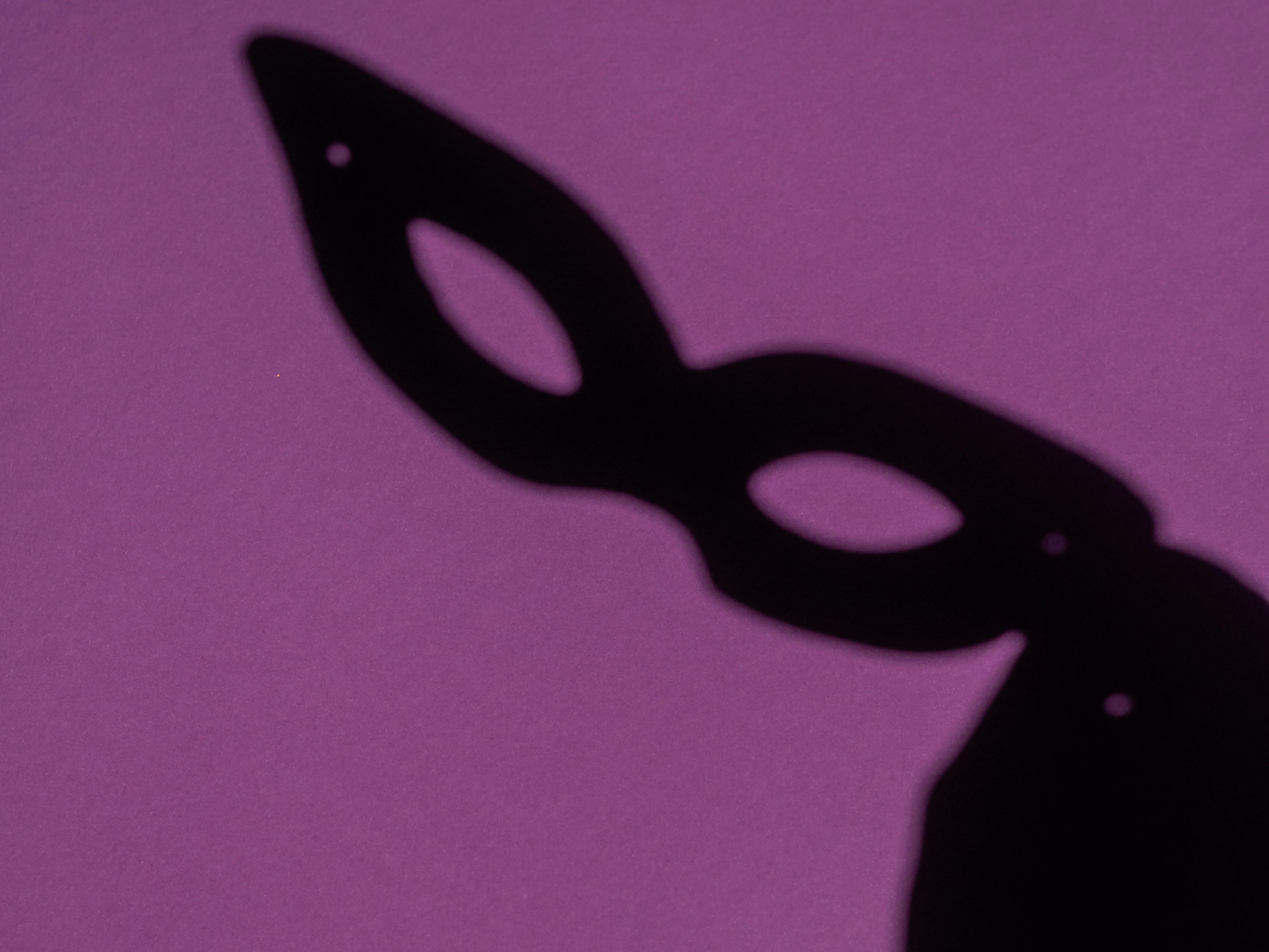KinseyInvestigations.com Background Check Screenings - The shadow of a theatrical face mask is cast on a purple background.