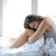 KinseyInvestigations.com cheating detective - A woman hugging her knees sits on a bed.