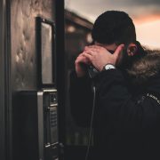 Kinsey Investigations Hire an Investigator to Find Someone - A man using a payphone conceals his face with his hand.