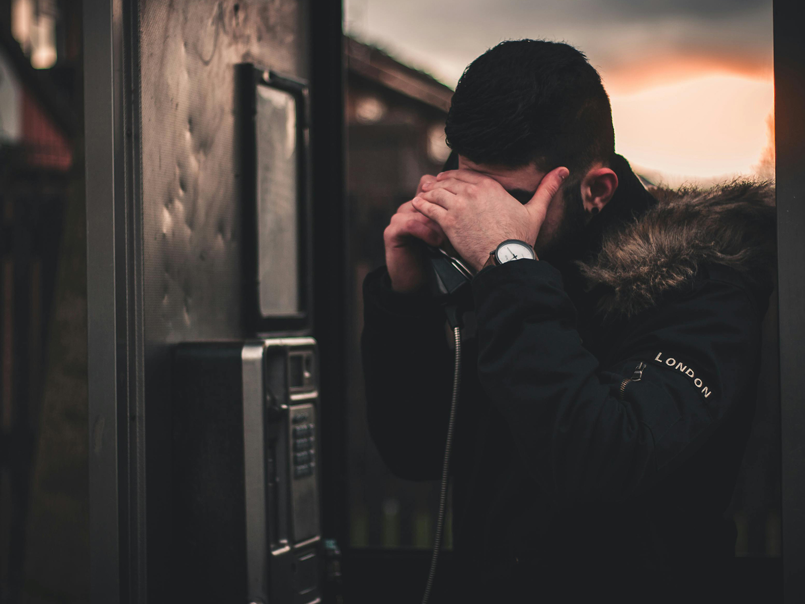 Kinsey Investigations Hire an Investigator to Find Someone - A man using a payphone conceals his face with his hand.
