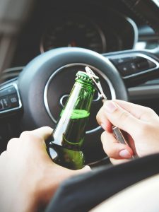 KinseyInvestigations.com Wrongful Death Investigations - Hands in front of a steering wheel prepare to pop a top off of a beverage bottle.