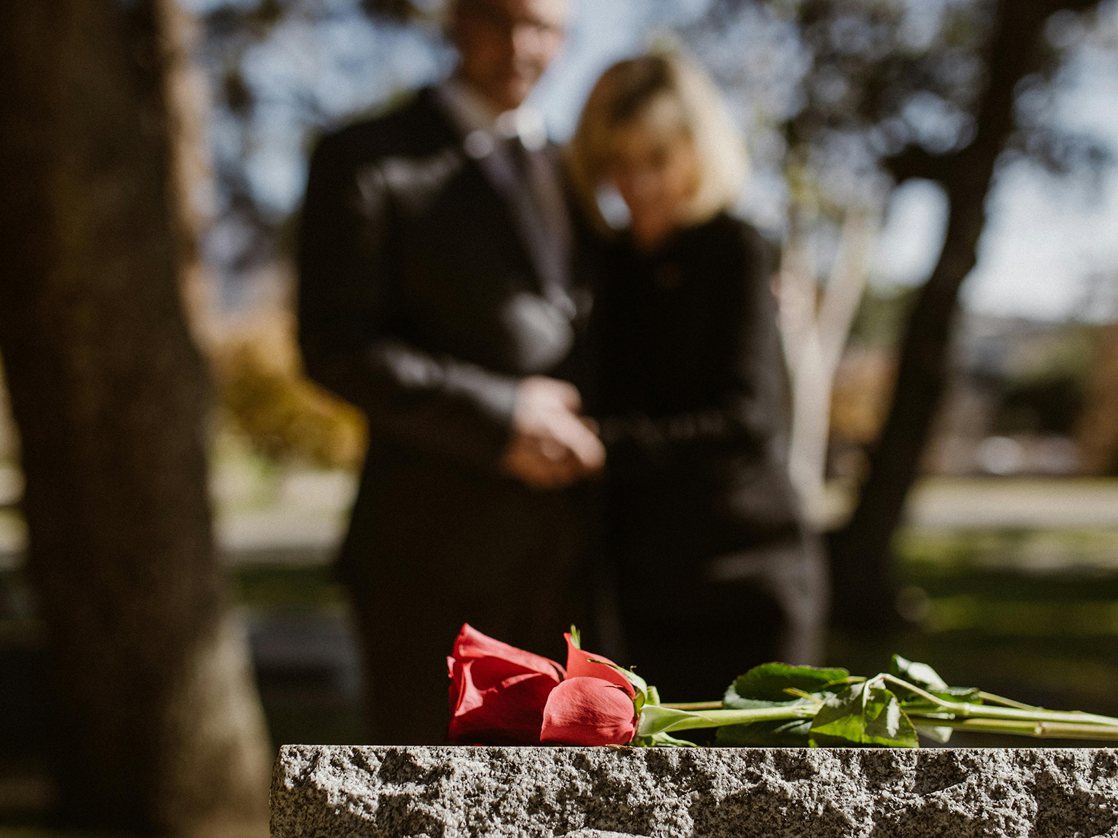 KinseyInvestigations.com Wrongful Death Investigations - A man and woman hold hands while looking at a grave stone.
