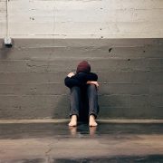 KinseyInvestigations.com Missing Person in L.A. - A barefoot person sits on the ground with their back to a cinder block wall.