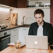 KinseyInvestigations.com Integrity Checks - A man works on a laptop at a kitchen table.