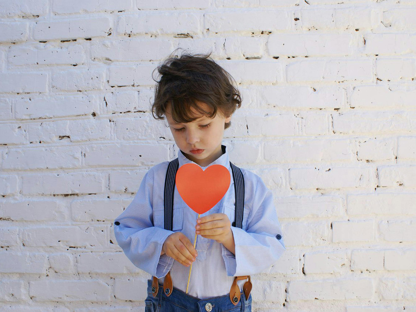KinseyInvestigations.com Child Custody - A young boy holds a paper heart in front of his chest.
