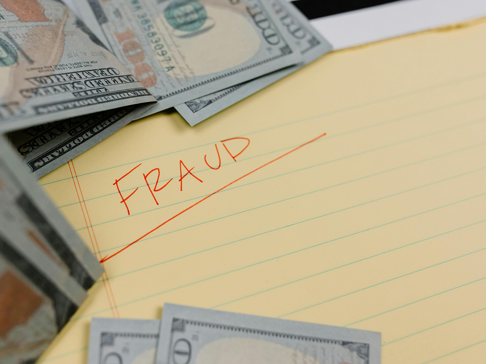 KinseyInvestigations.com Insurance Fraud Investigator - U.S. currency sits on top of a legal pad with the word fraud written across it.