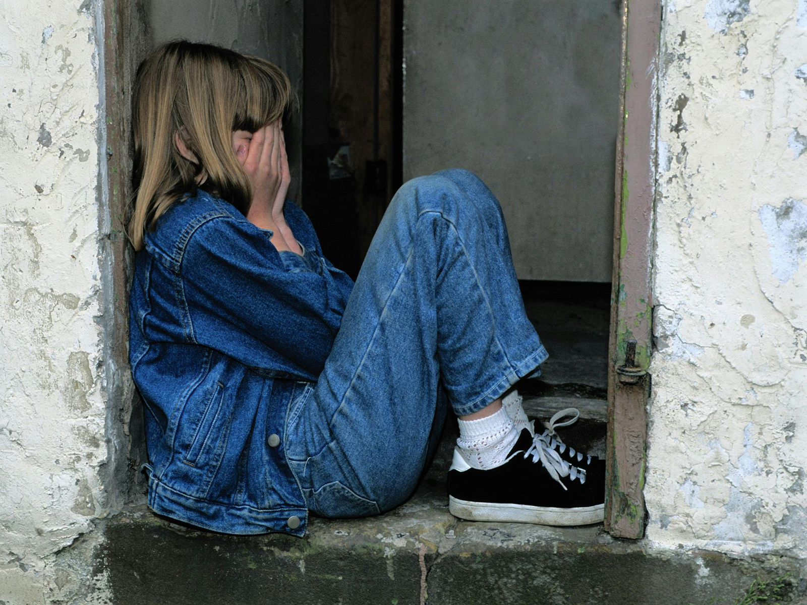 KinseyInvestigations.com Female Private Investigator Tips - A person with their hands over their face, sits in a doorway.