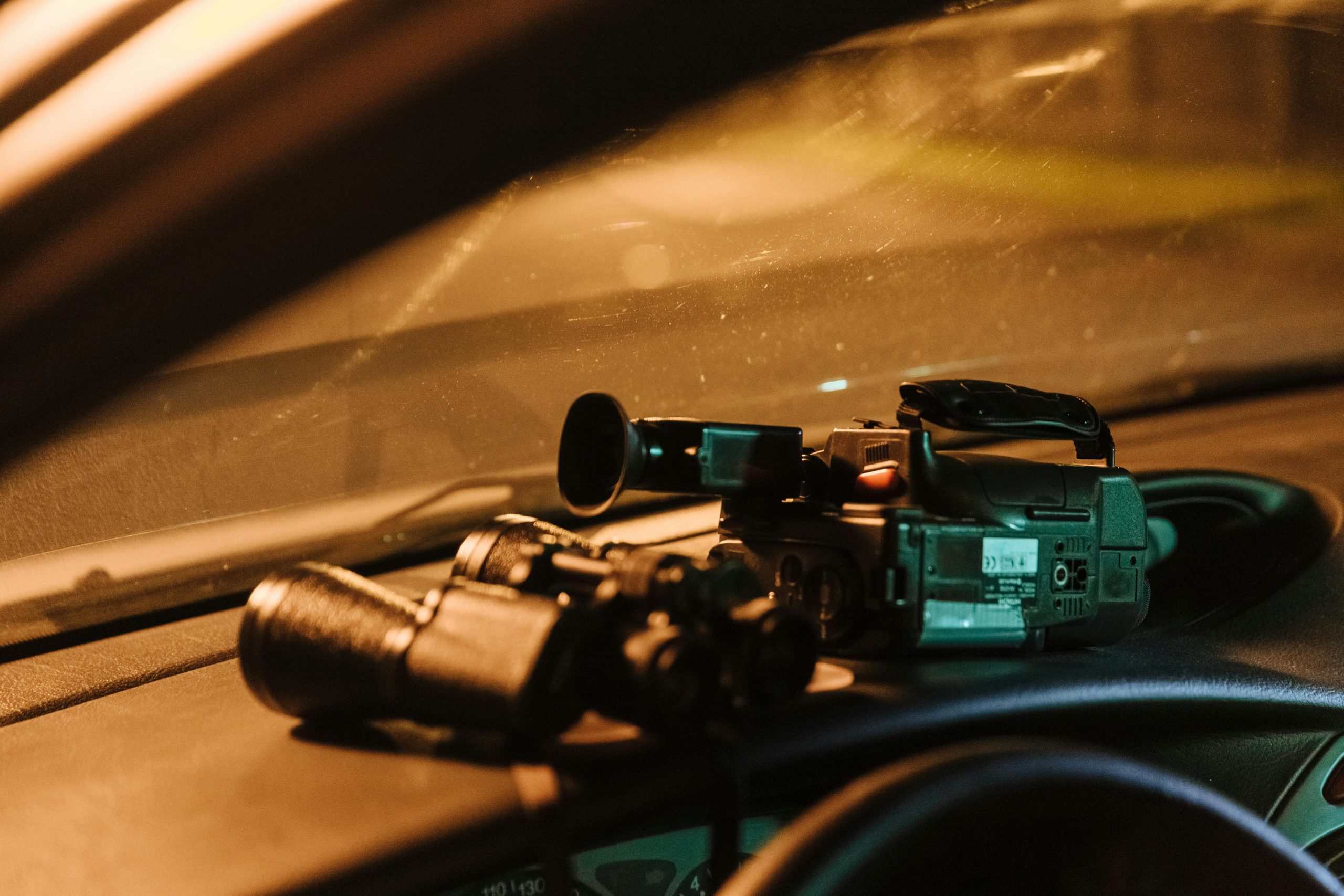 Video camera and binoculars on car dashboard - Visit KinseyInvestigations.com.