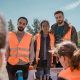 A group of people wearing high-visibility vests. One is looking at a missing persons flyer.