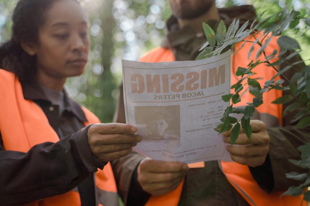 Two people in high-visibility vests looking at a missing persons poster - Consult Kinsey Investigations.