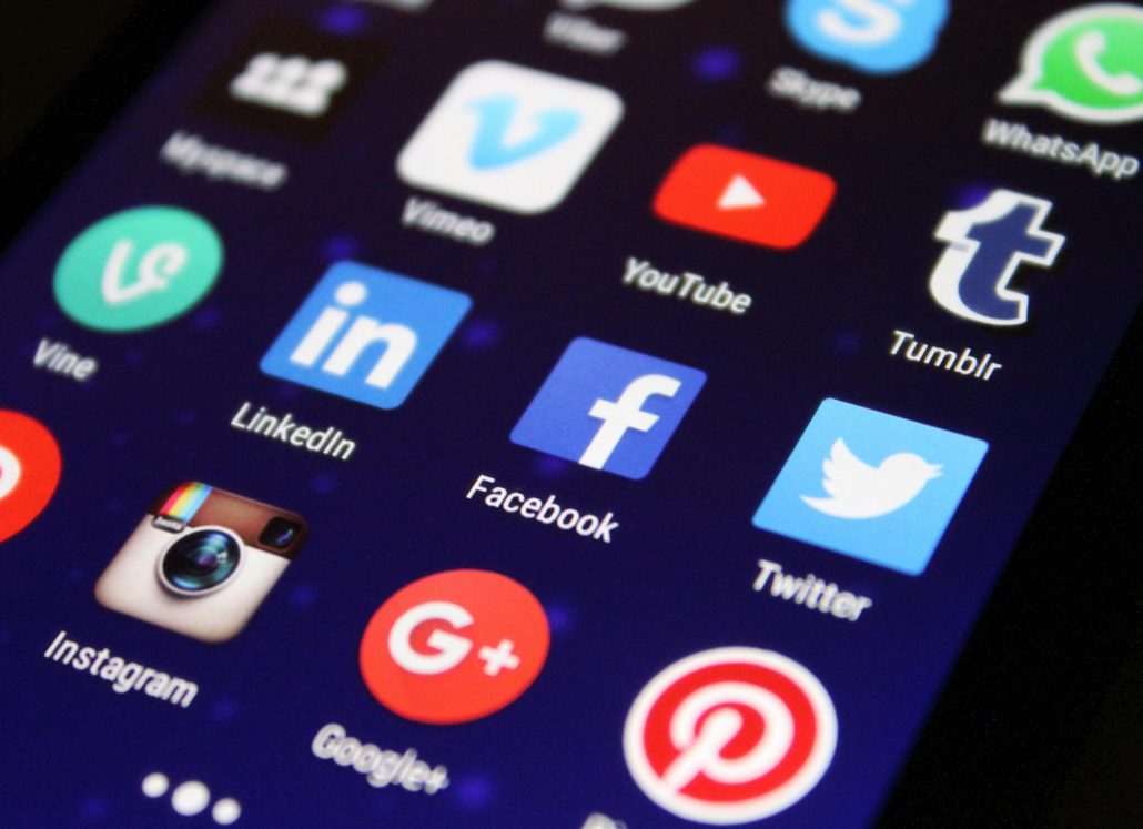 Social media icons on a phone screen - Visit KinseyInvestigations.com. 