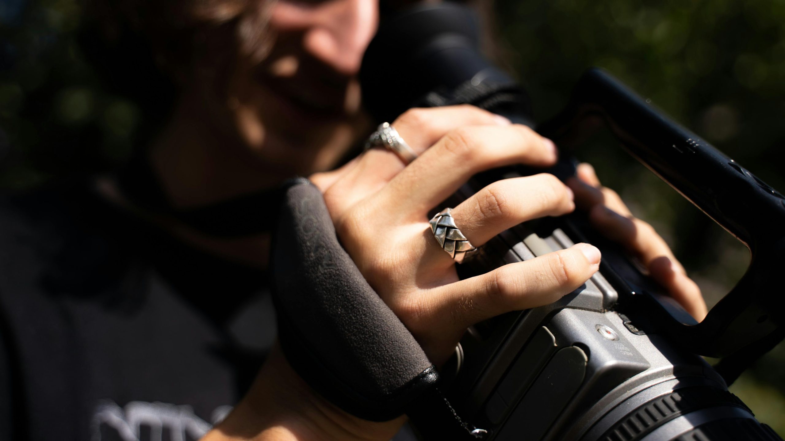 A woman's hands with silver rings holding a recording camera - Consult KinseyInvestigations.com.