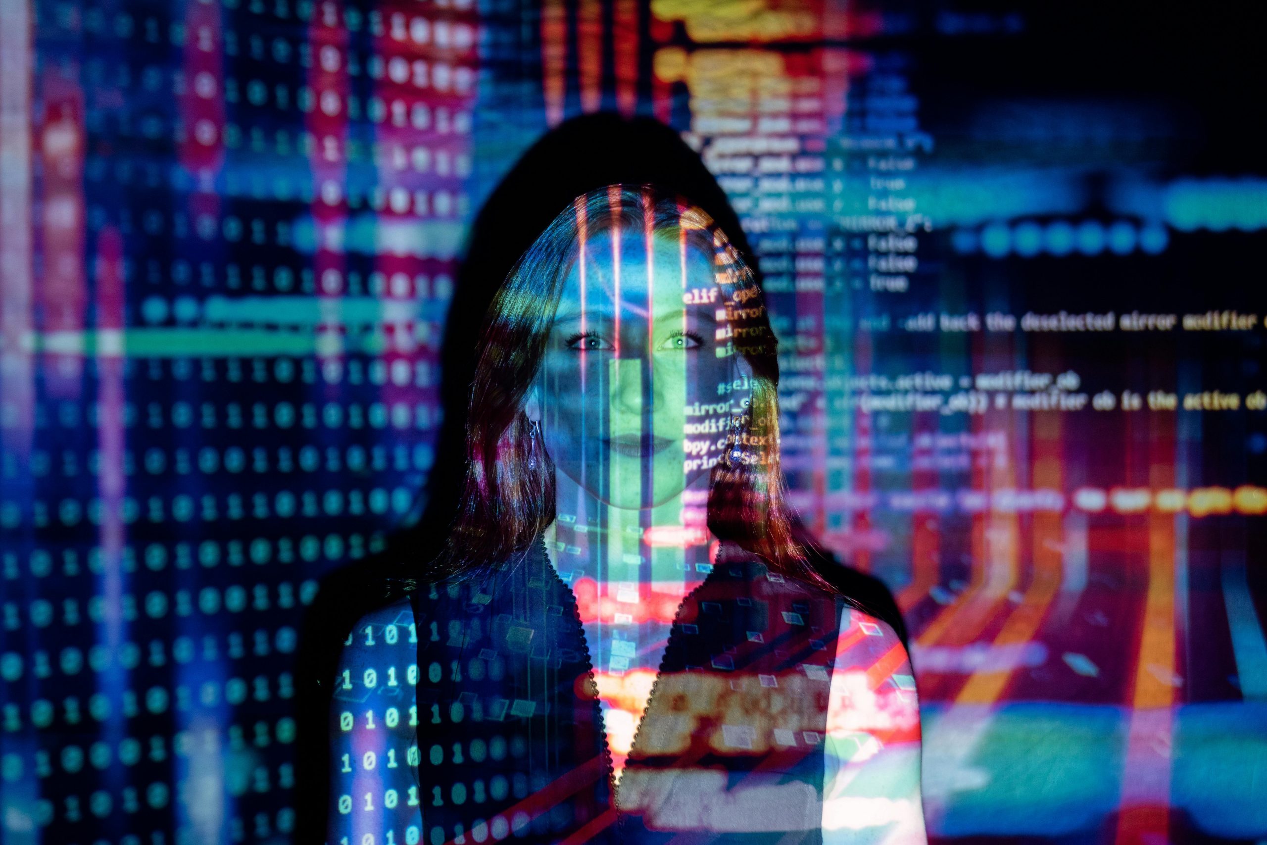Woman standing in front of colorful projection of computer coding - Consult Kinsey Investigations.