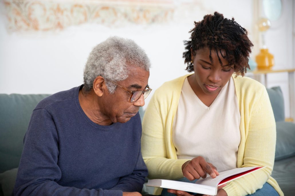 A younger woman showing an elderly man something in a book - Contact Kinsey Investigations. 