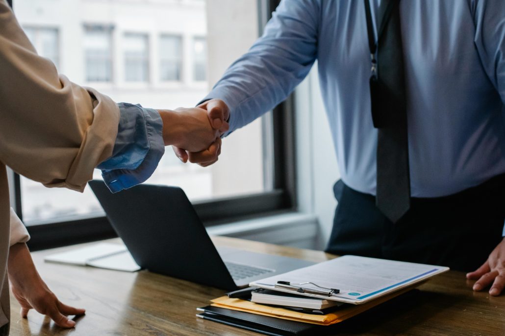 A female private investigator seen from below the shoulders shaking hands with a client - Consult Kinsey Investigations. 